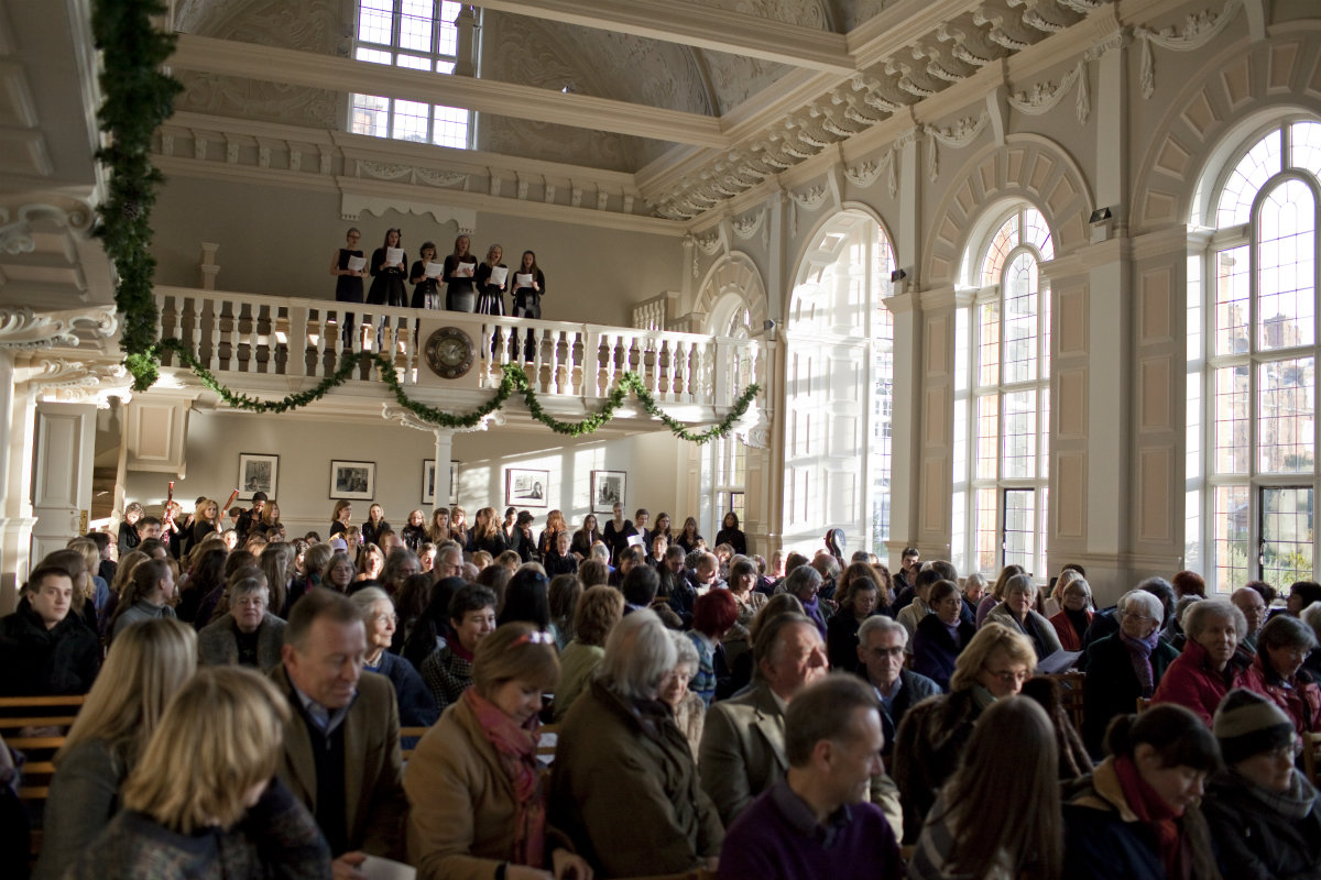 Choir singing from balcony to packed audience
