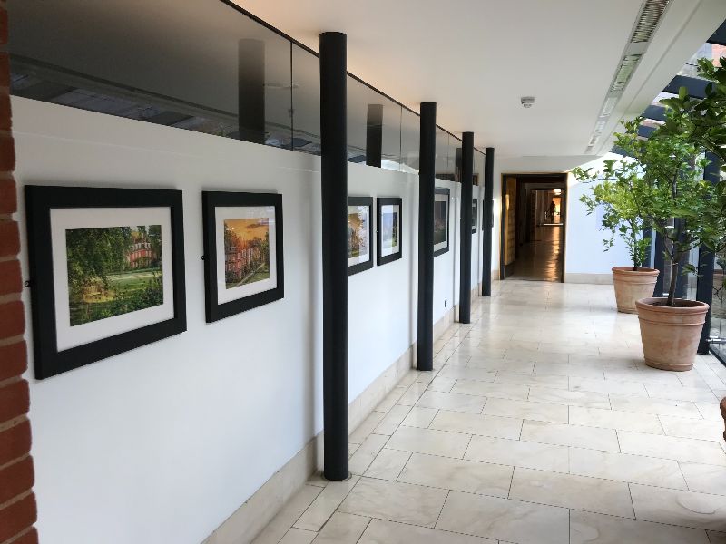 An exhibition of photography in a glass-walled corridor