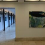 An oil painting hanging on a corridor wall, others visible behind it