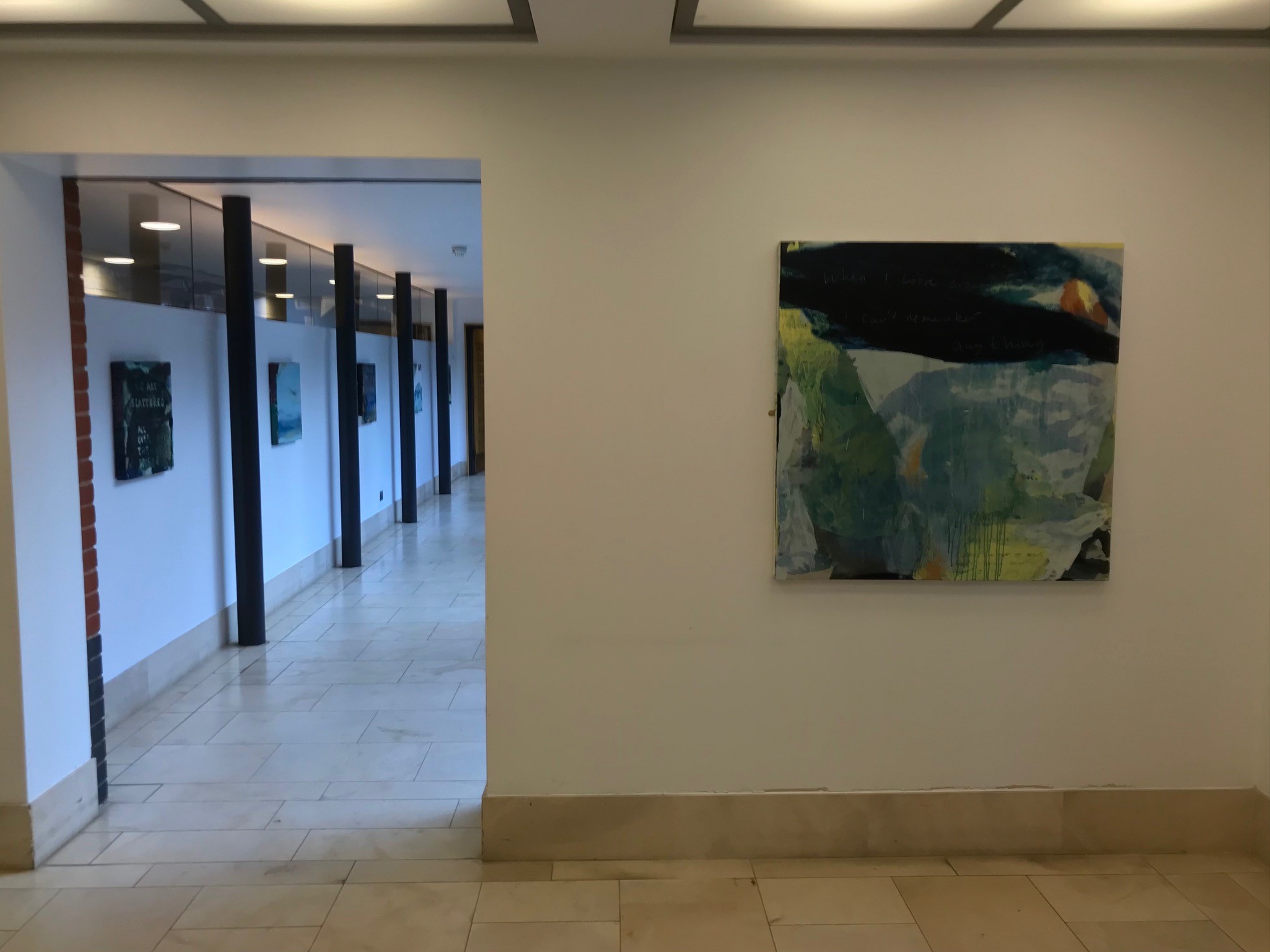 An oil painting hanging on a corridor wall, others visible behind it