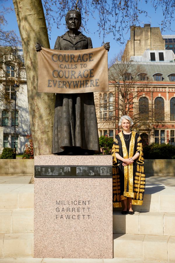 Dame Vivien Rose, in court robes, stands beside the statue of Dame Millicent Garrett Fawcett