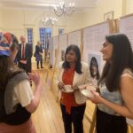 Rupa Huq MP and two students standing in front of a display board